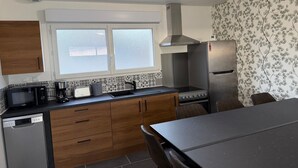 Eine Küche mit Holzausstattung, einer Mikrowelle, einer Kaffeemaschine, einem Herd und einem Kühlschrank.