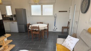 A living room with a sofa, a coffee table, a TV, and a dining area with a table and chairs. - Holiday Home “Gîte Des 3M” with Private Terrace (Leubringhen)