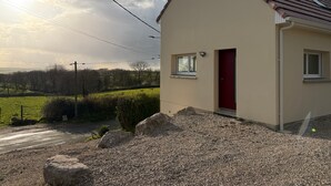 A single-story building with a red door, a small window, and a gravel driveway. - Holiday Home “Gîte Des 3M” with Private Terrace (Leubringhen)