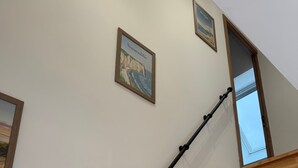 A wooden staircase with a black handrail, white walls, and two framed pictures. - Holiday Home “Gîte Des 3M” with Private Terrace (Leubringhen)