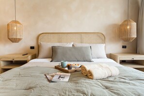 A neatly made bed with a magazine, a bowl of fruit, and a remote control on a wooden nightstand. - Spacious 4 Bedroom Apartment near Arauco Park (Santiago)