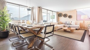 Een moderne woonkamer met een eethoek, grote ramen en uitzicht op bergen.