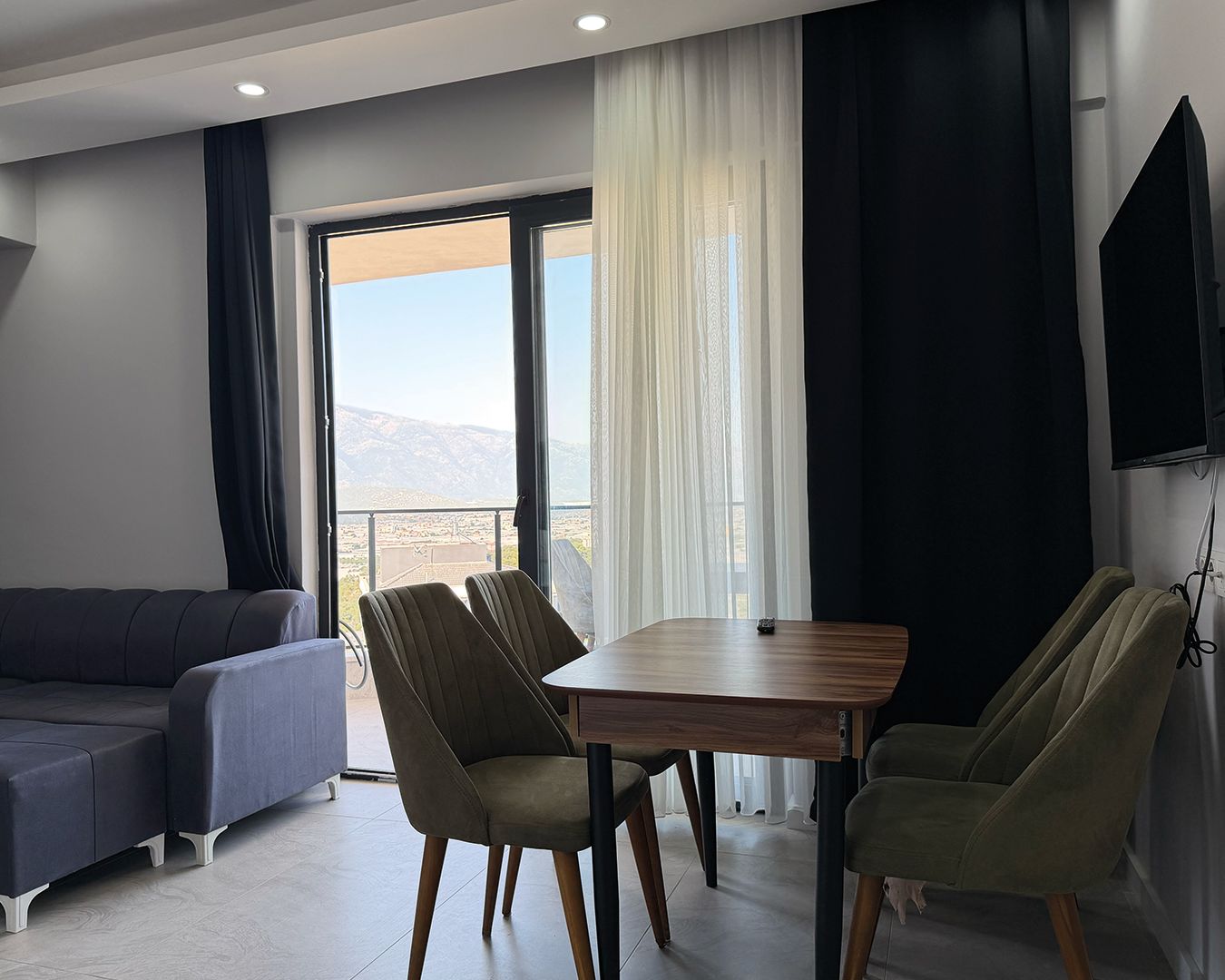 Una sala de estar moderna con un sofá, dos sillones, una mesa y un amplio ventanal con vistas al exterior.
