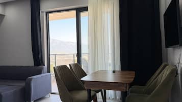 Una sala de estar moderna con un sofá, dos sillones, una mesa y un amplio ventanal con vistas al exterior.