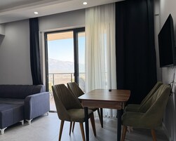 Una sala de estar moderna con un sofá, dos sillones, una mesa y un amplio ventanal con vistas al exterior.
