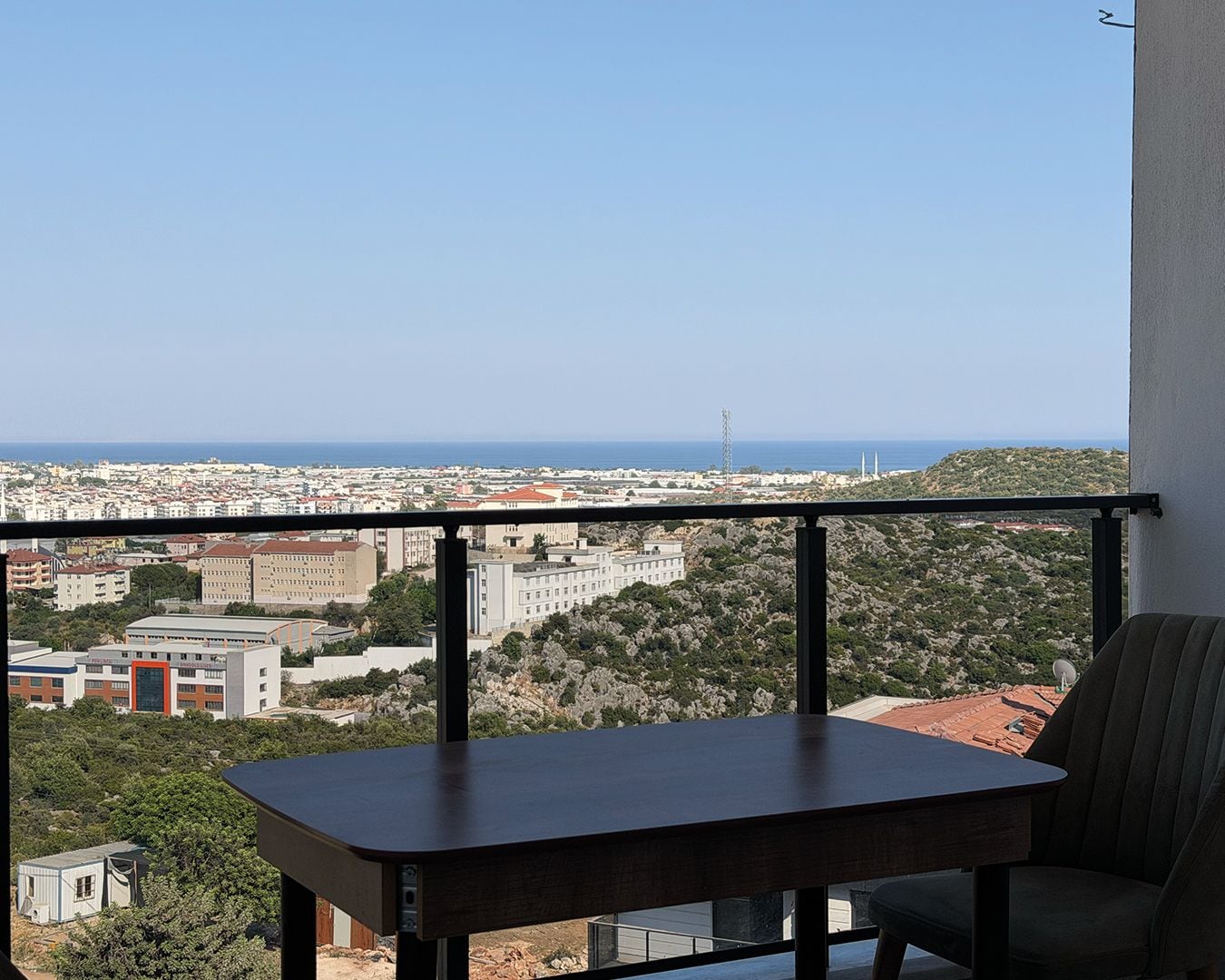 Ein Balkon mit Blick auf eine Stadtlandschaft und das Meer.