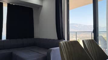 Una sala de estar moderna con un sofá modular, una mesa de comedor y un amplio ventanal con vistas a la montaña.