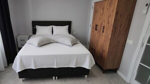 A bedroom with a bed, bedside tables, a wardrobe, and a window with curtains. - Doğuş Apart (Antalya)