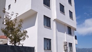 A multi-story building with a white facade, multiple windows, and air conditioning units. - Doğuş Apart (Antalya)