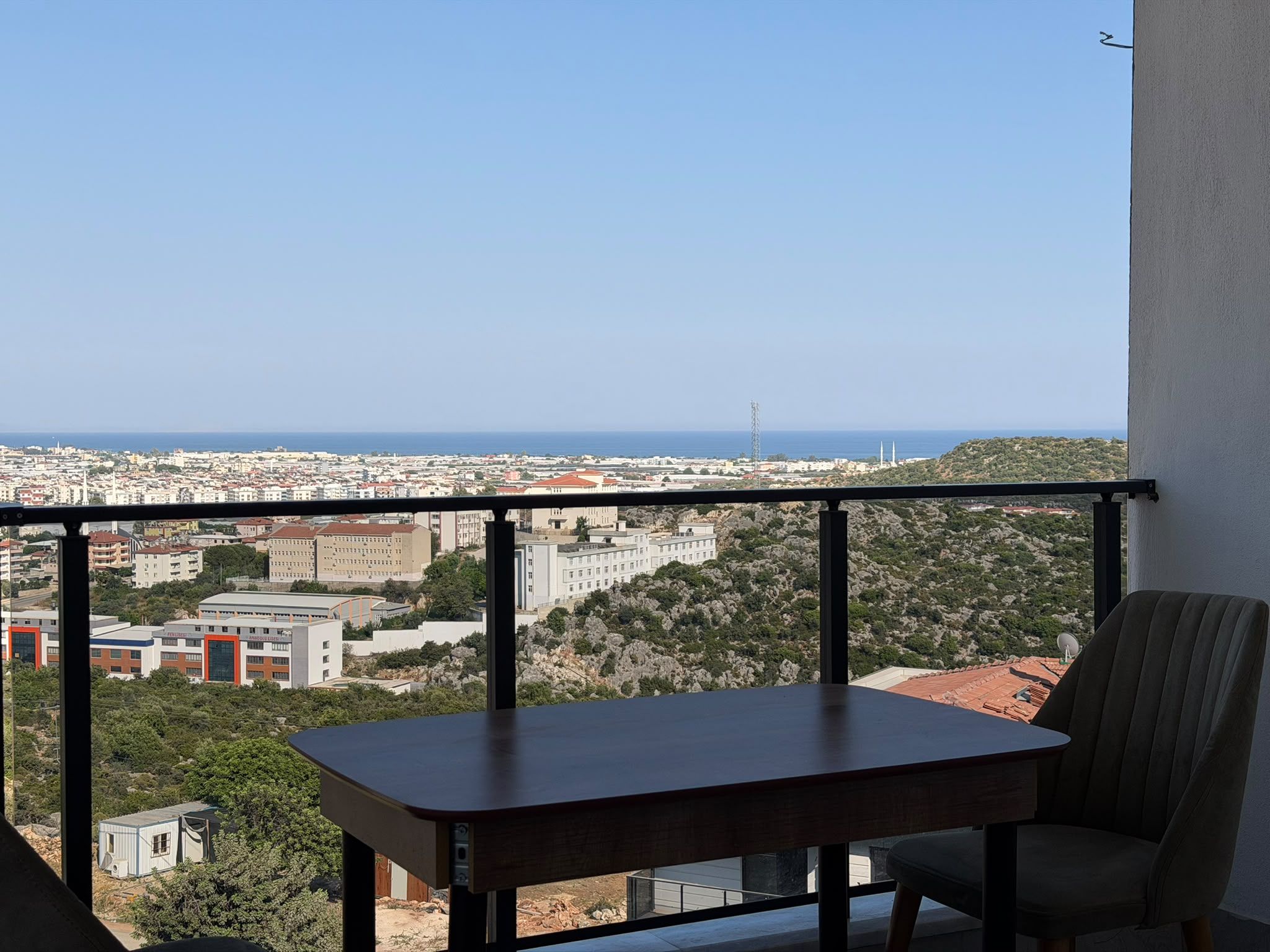 Ein Balkon mit Blick auf eine Stadtlandschaft und das Meer.