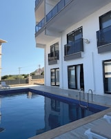 Un edificio moderno con piscina, balcones y cielo despejado.