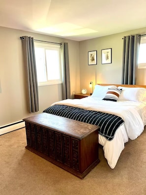 A bedroom with a bed, bedside table, lamp, and a window with curtains.
