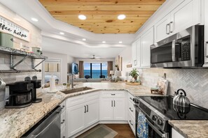 A modern kitchen with white cabinets, a black stove, and a microwave. - NEW | Beachfront Luxury · Beach Setup Included 🌊 (Panama City Beach)