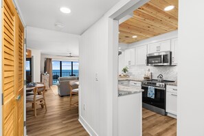 A modern kitchen with white cabinetry, a stainless steel microwave, and an oven. - NEW | Beachfront Luxury · Beach Setup Included 🌊 (Panama City Beach)