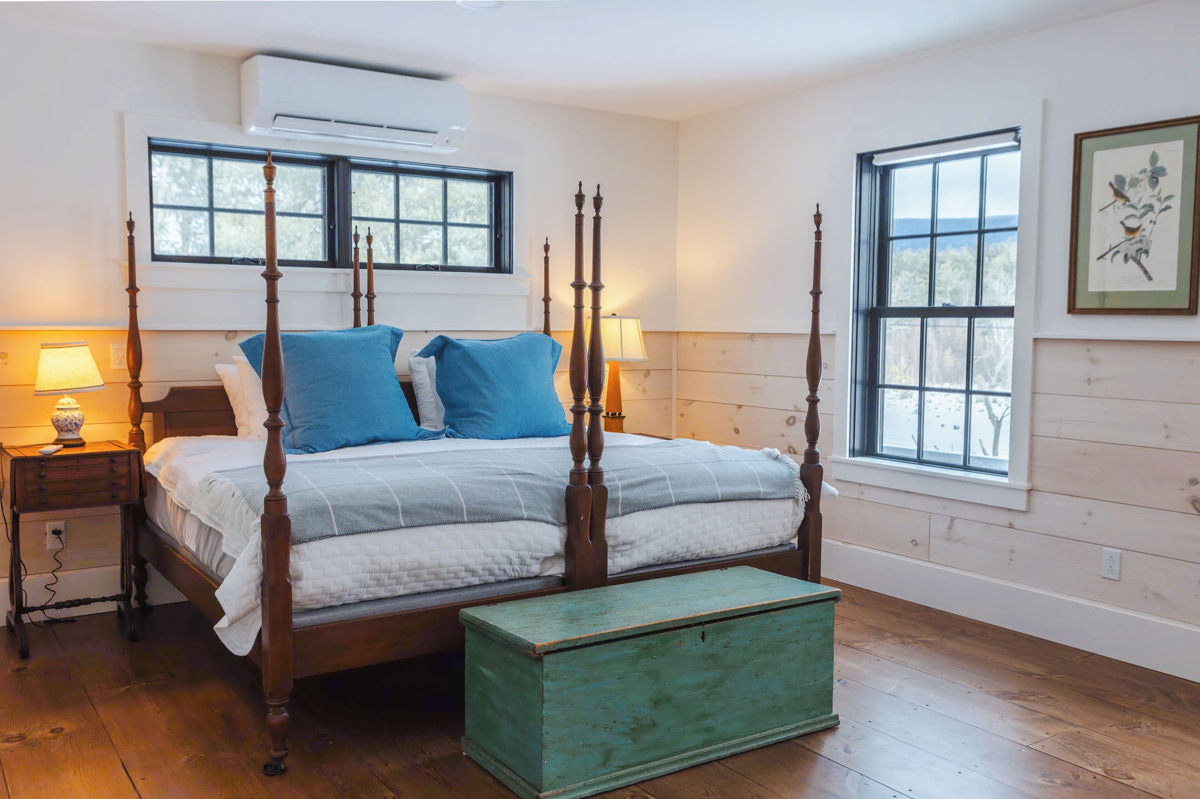 A four-poster bed with a wooden headboard, a green chest of drawers, and two bedside lamps.