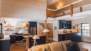 Un vaste espace de vie comprenant une cuisine, un coin repas et une chambre en mezzanine.