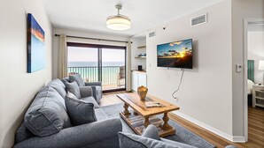A modern living room with a sofa, a coffee table, a TV, and a balcony with a view. - Sundunes 173 (Navarre)
