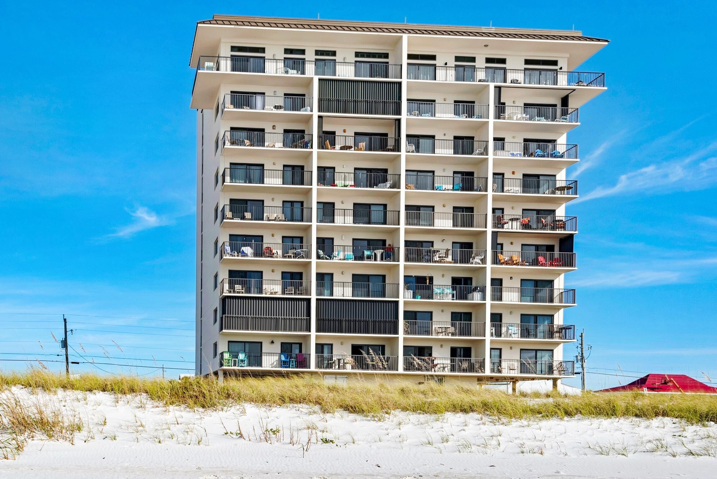 Un hôtel à plusieurs étages doté de balcons, situé près d’une plage.