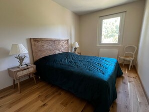 A bedroom with a wooden headboard, a single bed, a nightstand with a lamp, a chair, and a window with natural light. - Provencal house with private pool (Salernes)