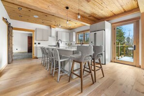 Eine moderne Küche mit Holzboden, weißen Schränken und einer großen Kochinsel mit Barhocker.