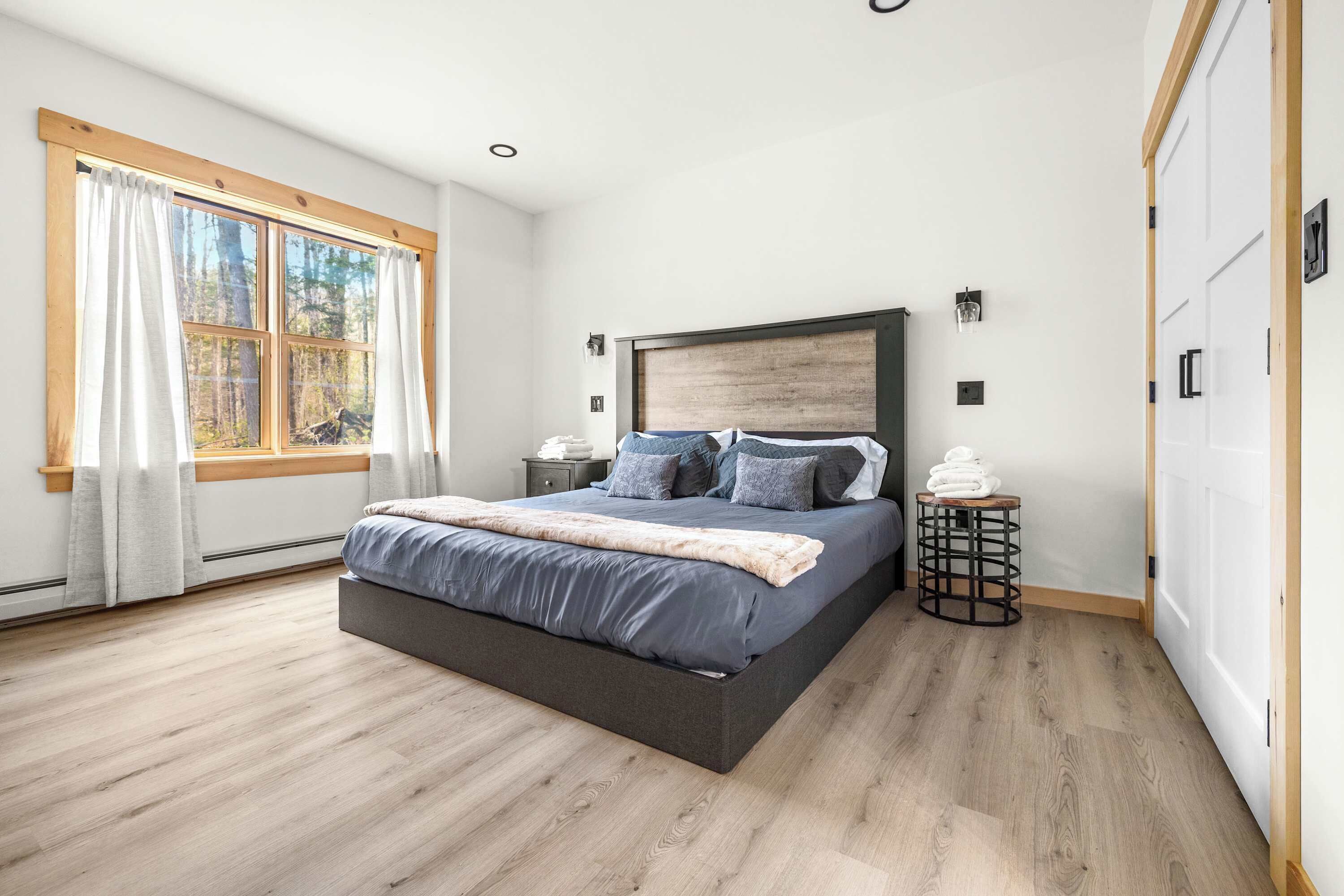 Quarto com uma cama grande, uma janela com cortinas, uma mesa de cabeceira e um guarda-roupa.