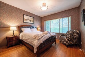 A bedroom with a bed, nightstand, chair, and a large window. - Modern Private Garden Suite Near UBC & Pacific Spirit Park
Free Parking (Vancouver)