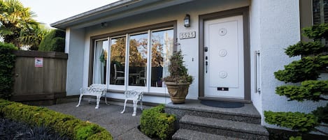 Un bâtiment avec une porte blanche portant le numéro « 5525 », un petit porche avec un banc et un pot de fleurs.