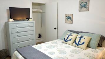 Une chambre à coucher avec un lit, une commode, un téléviseur et des œuvres d’art accrochées au mur.