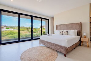 Ein Schlafzimmer mit einem großen Bett, Blick ins Freie und einem kleinen Nachttisch.