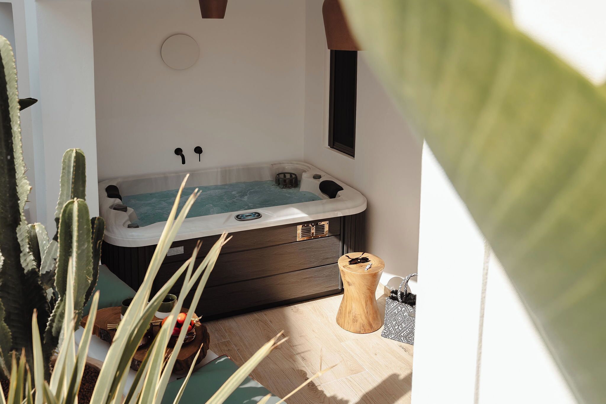 A spa area with a hot tub, wooden stool, and cacti.