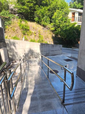 Eine Betonstiege mit Metallgeländern führt zu einem Gebäude mit einem Balkon.