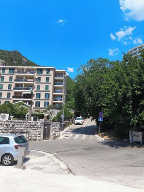 Ein mehrstöckiges Gebäude mit Balkonen, einer Steinmauer und einem geparkten Auto davor.