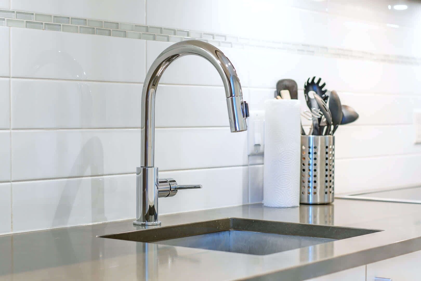 A modern kitchen with a stainless steel faucet, a sink, and a utensil holder with a roll of paper towels.