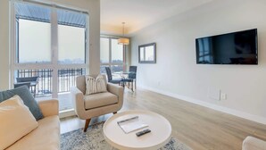 A modern living room with a sofa, armchair, coffee table, and a TV mounted on the wall. - Serene and Calming Downtown Suite (Victoria)