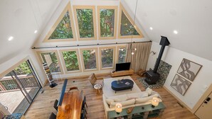 Een ruime loft met een hoge nok, grote ramen, een open haard en een eetgedeelte.