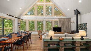 Een ruime loft met een eethoek, een woonkamer met open haard, en grote ramen met uitzicht op de omgeving.