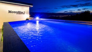 A nighttime view of a swimming pool with a sign reading 'MonteBliss 2 BY HOLIDAY HOME.'