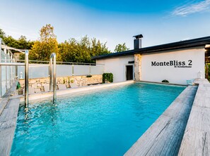 Ein Schwimmbecken mit einer Steinmauer und einem Metallgeländer, einer Steintreppe und einem Gebäude mit der Beschilderung 'MonteBliss 2 By HolidayHome'.