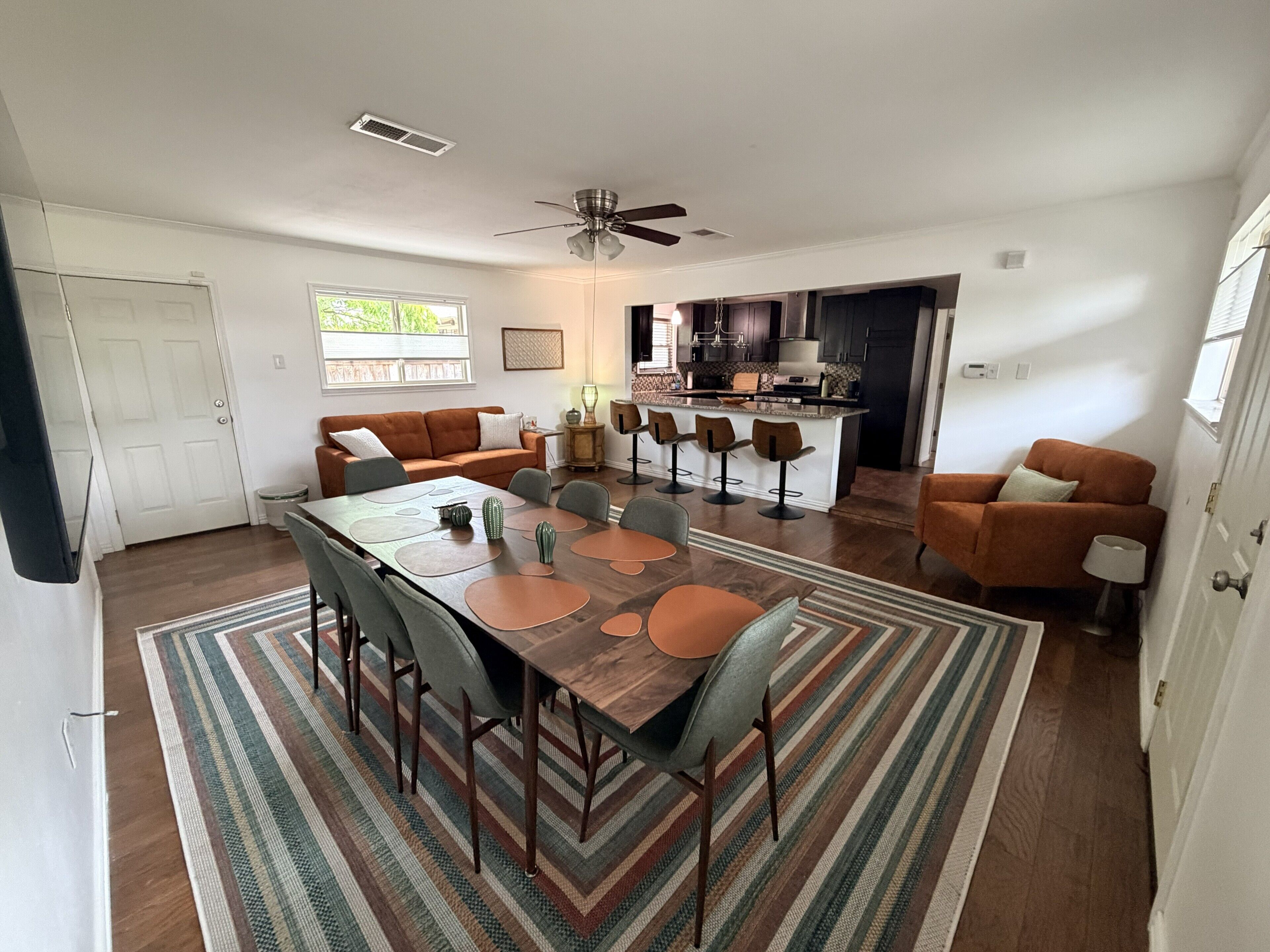 A dining area with a wooden table, chairs, and a patterned rug.