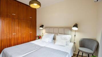 A bedroom with a bed, bedside lamps, a chair, and a wooden wardrobe.