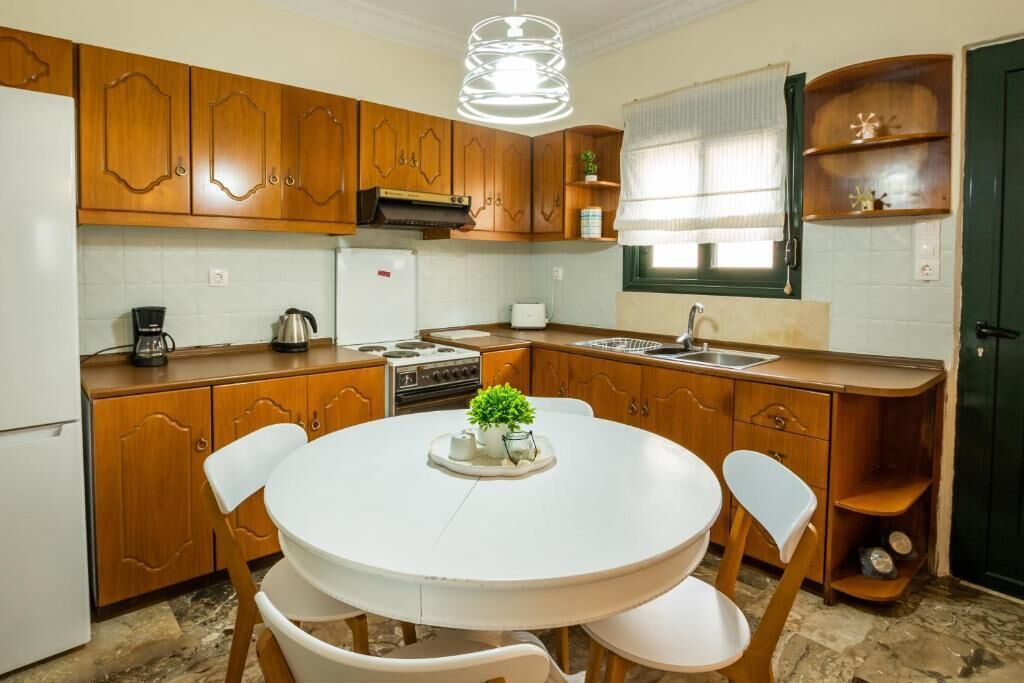 Una cocina con armarios de madera, una mesa de comedor blanca y sillas.