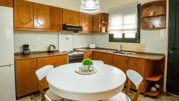 Una cocina con armarios de madera, una mesa de comedor blanca y sillas.