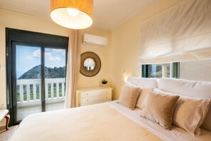 Un dormitorio con cama, cómoda, espejo y balcón con vistas a la montaña.