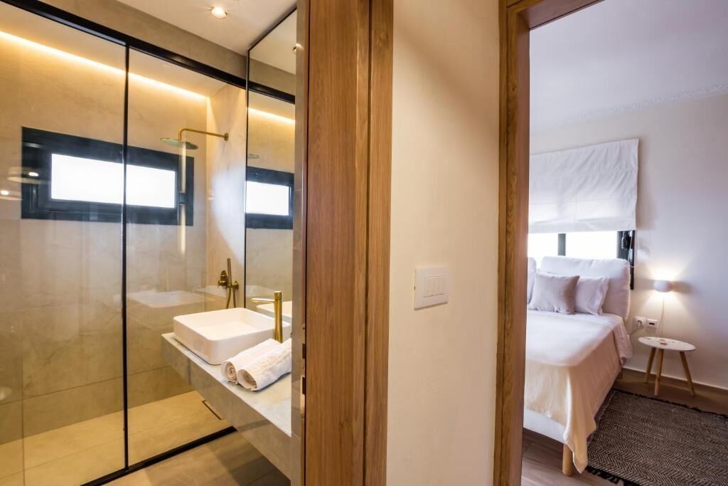 Un baño moderno con cabina de ducha de vidrio, un lavamanos blanco y un espejo.