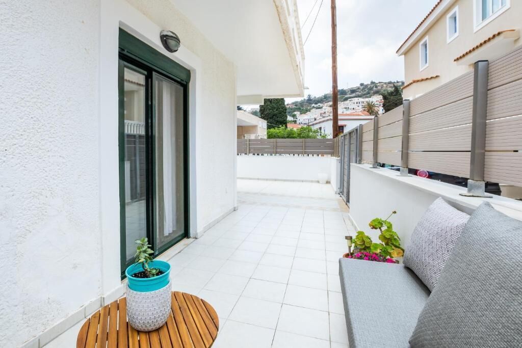 A balcony with a wooden table, a sofa, and potted plants.