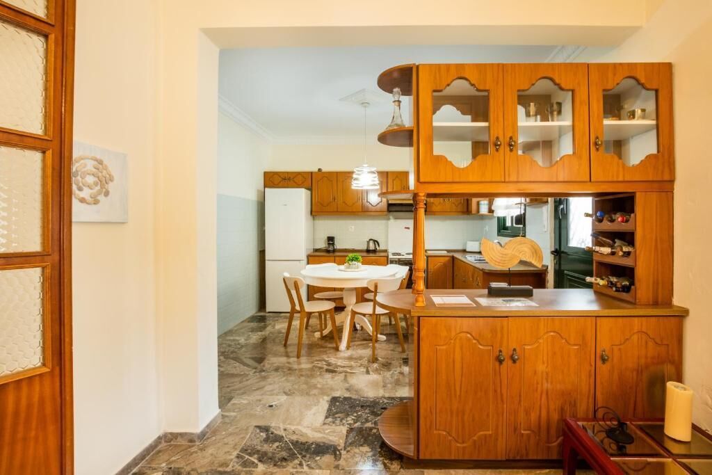 Una cocina con armarios de madera, una mesa de comedor, sillas y piso de mármol.