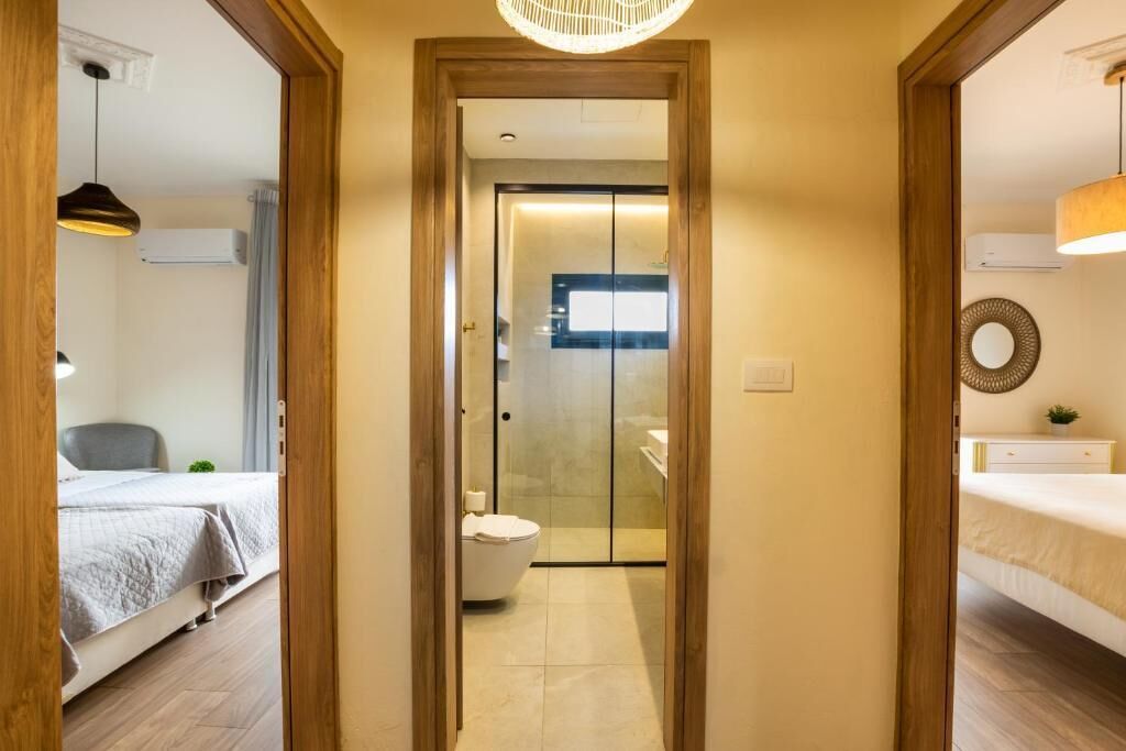 A hallway leading to a bathroom with a toilet and a shower.