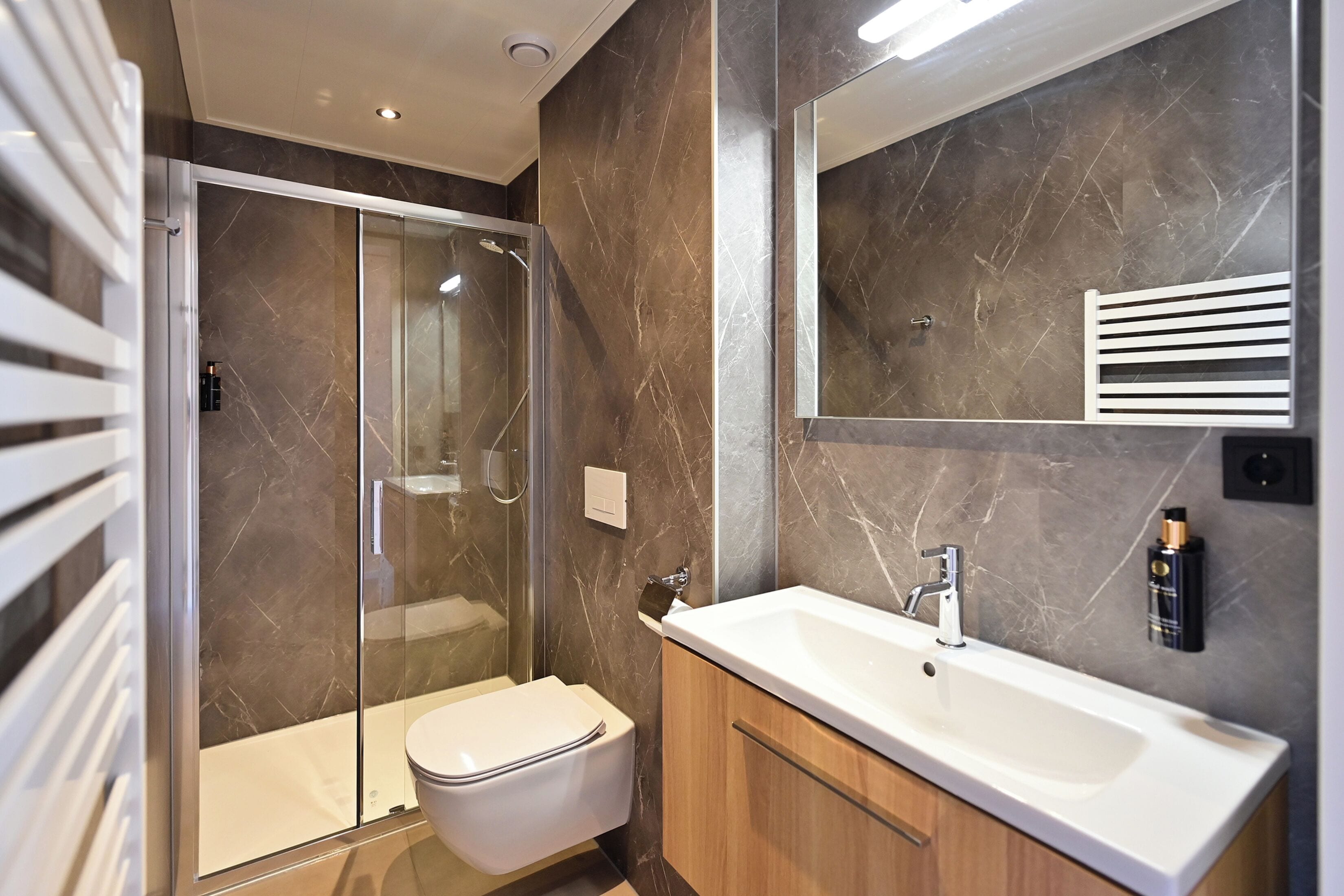 Un baño moderno con ducha envuelta en vidrio, inodoro blanco y tocador con espejo.
