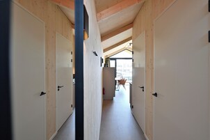 Un pasillo con paredes y puertas de madera que conduce a un comedor con sillas y una mesa.