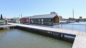 A waterfront property with a dock extending into the water, a small building with a sloped roof, and a clear sky.
